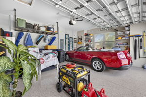 Garage features overhead storage, shelves with hanging brackets, a portable generator, and is oversized.