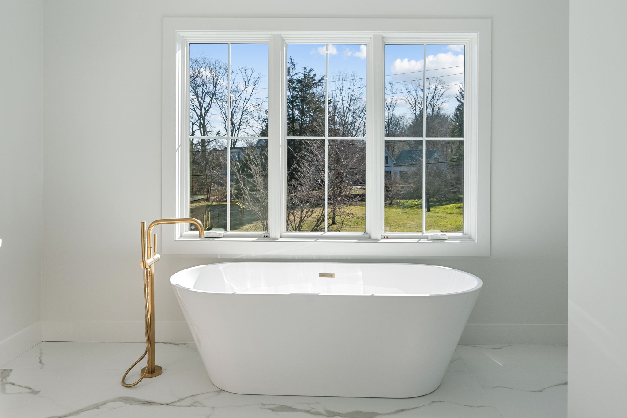 Freestanding soaking tub with waterfall feature and handheld shower