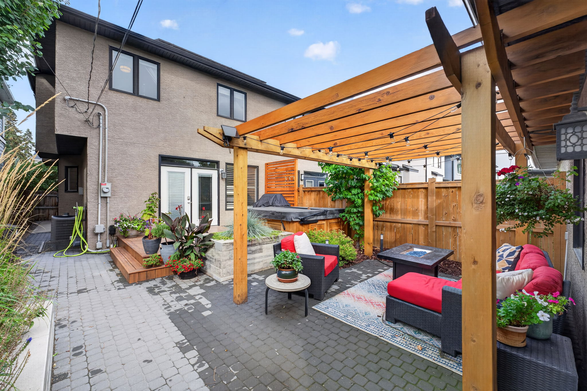 Pergola-covered lounge, paved patio and hot tub deck out back