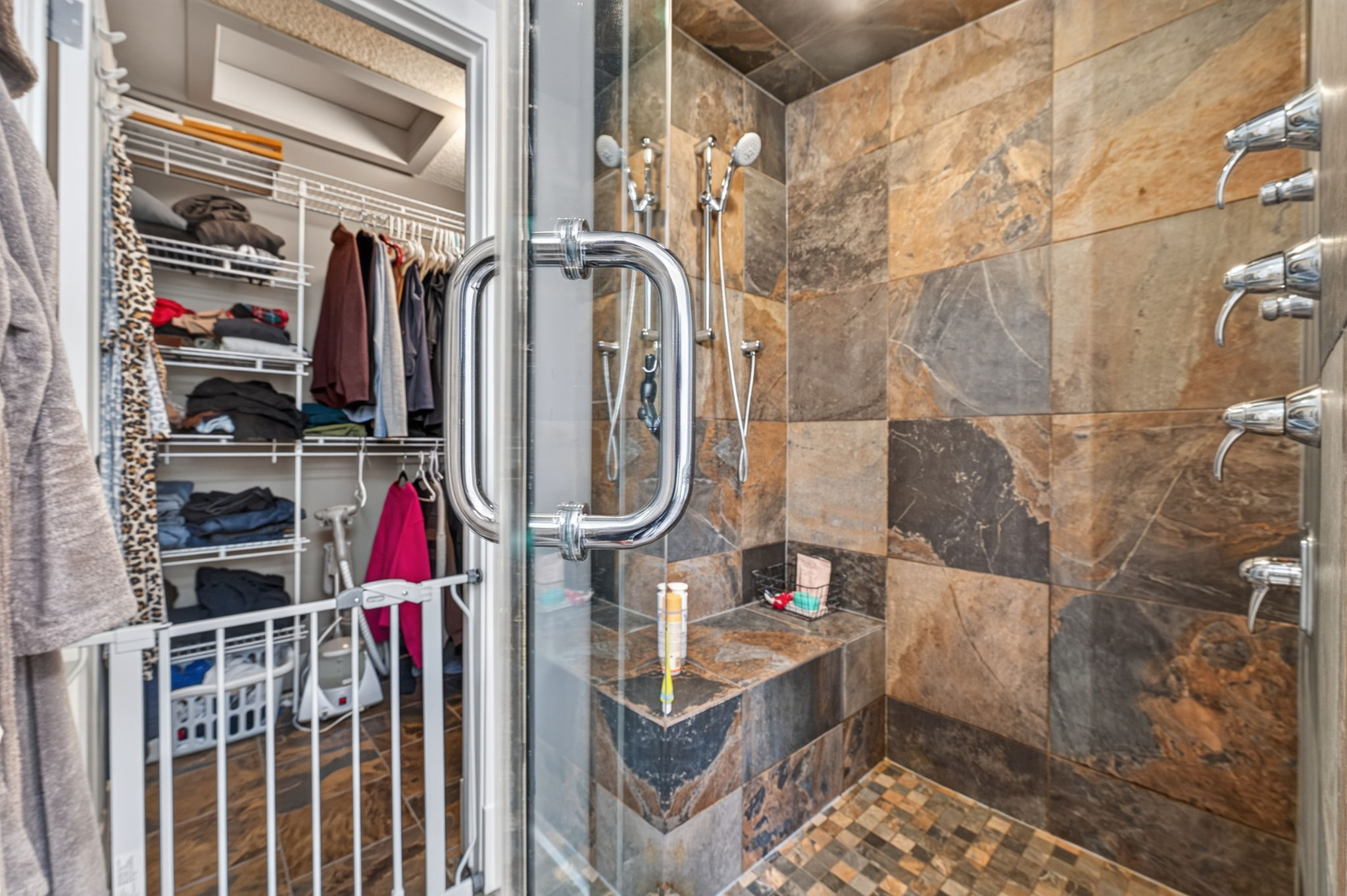 Slate steam shower with body jets and a fitted walk-in closet beyond