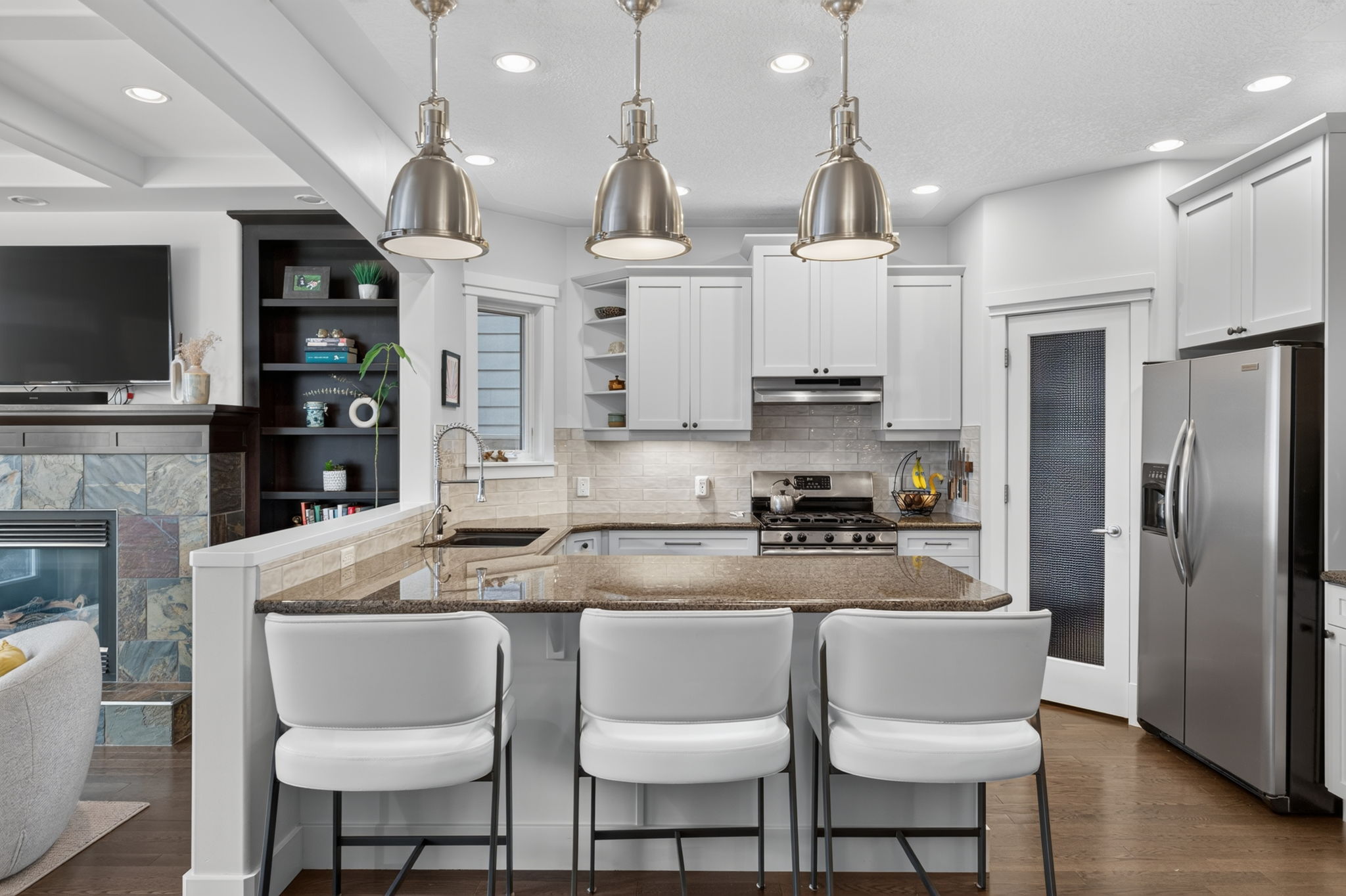 White kitchen with a granite island, gas range and stainless appliances
