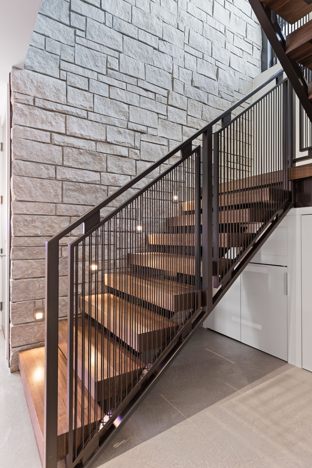 Lower level walnut stairs with stone as the backdrop.