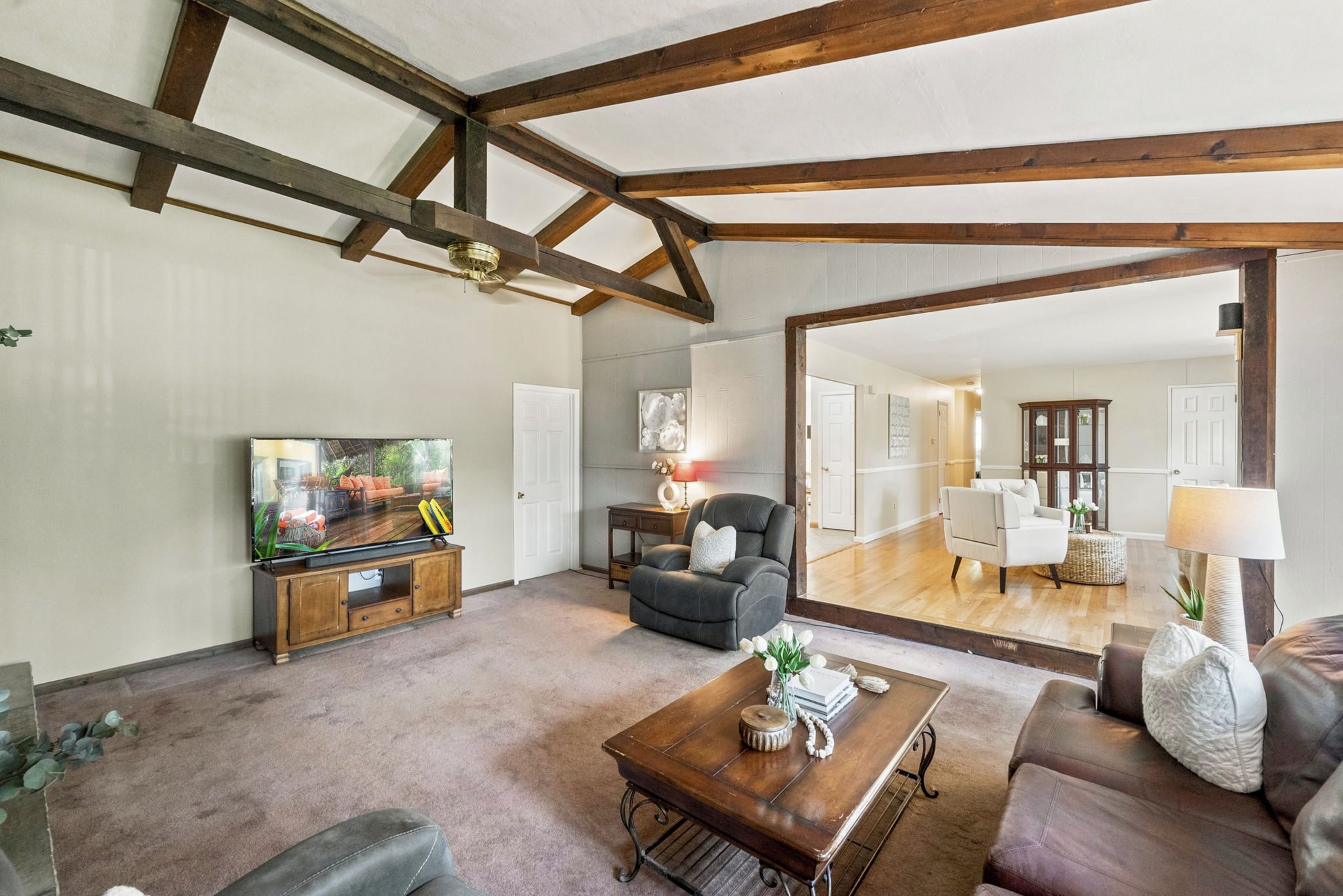 Inside, the spacious great room makes an immediate impression with its soaring cathedral ceiling, exposed dark wood beams, dramatic center truss and full brick wall with a wood-burning fireplace. The large eat-in kitchen features a center island and sliding doors leading to an impressive 25-by-25-foot deck overlooking a private, tree-lined backyard.
