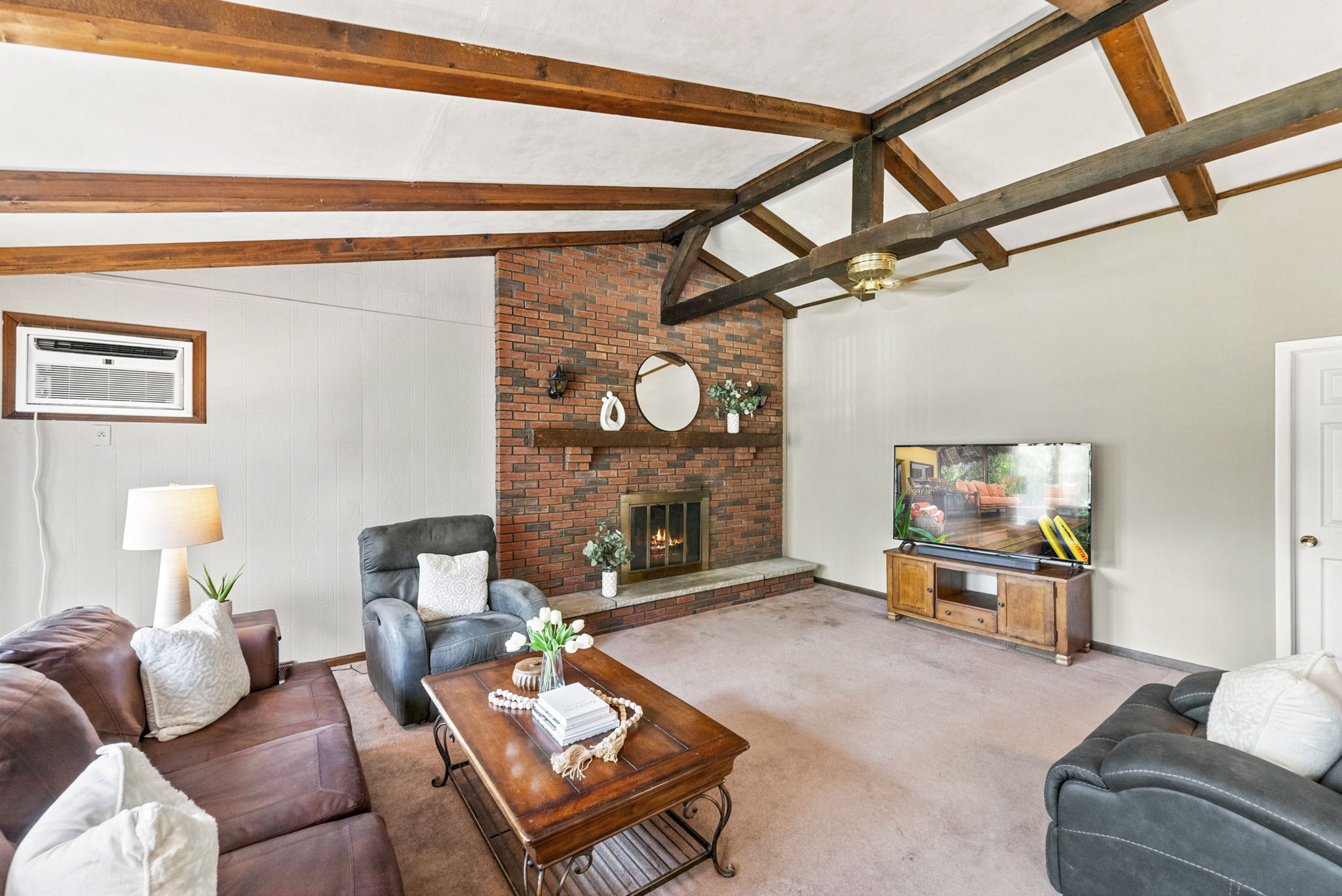 Inside, the spacious great room makes an immediate impression with its soaring cathedral ceiling, exposed dark wood beams, dramatic center truss and full brick wall with a wood-burning fireplace. The large eat-in kitchen features a center island and sliding doors leading to an impressive 25-by-25-foot deck overlooking a private, tree-lined backyard.