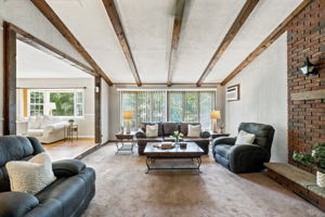 Inside, the spacious great room makes an immediate impression with its soaring cathedral ceiling, exposed dark wood beams, dramatic center truss and full brick wall with a wood-burning fireplace. The large eat-in kitchen features a center island and sliding doors leading to an impressive 25-by-25-foot deck overlooking a private, tree-lined backyard.