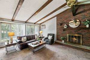 Inside, the spacious great room makes an immediate impression with its soaring cathedral ceiling, exposed dark wood beams, dramatic center truss and full brick wall with a wood-burning fireplace. The large eat-in kitchen features a center island and sliding doors leading to an impressive 25-by-25-foot deck overlooking a private, tree-lined backyard.