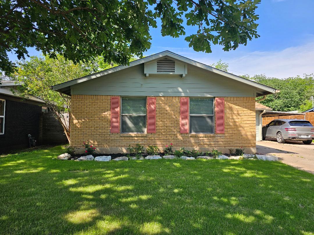 Single-story residence featuring light-colored brick siding, coordinating gable roof and a carport.