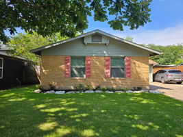 Single-story residence featuring light-colored brick siding, coordinating gable roof and a carport.