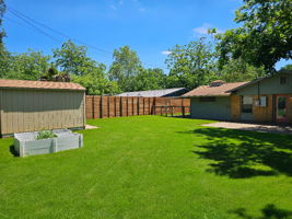 Spacious backyard featuring a wood privacy fence, a Tuff Shed and a paved patio area, See the acces to the carport on the left.