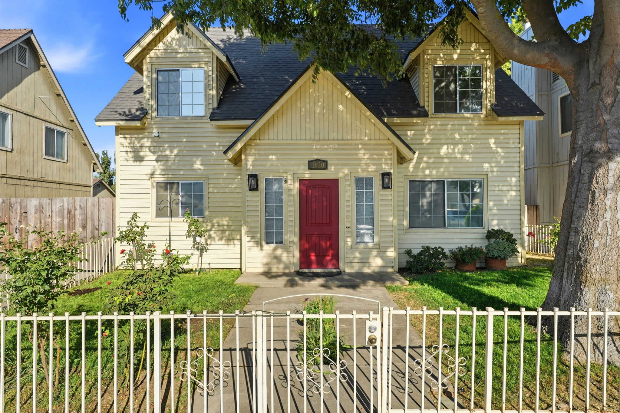 Front exterior with red entry door and mature shade tree