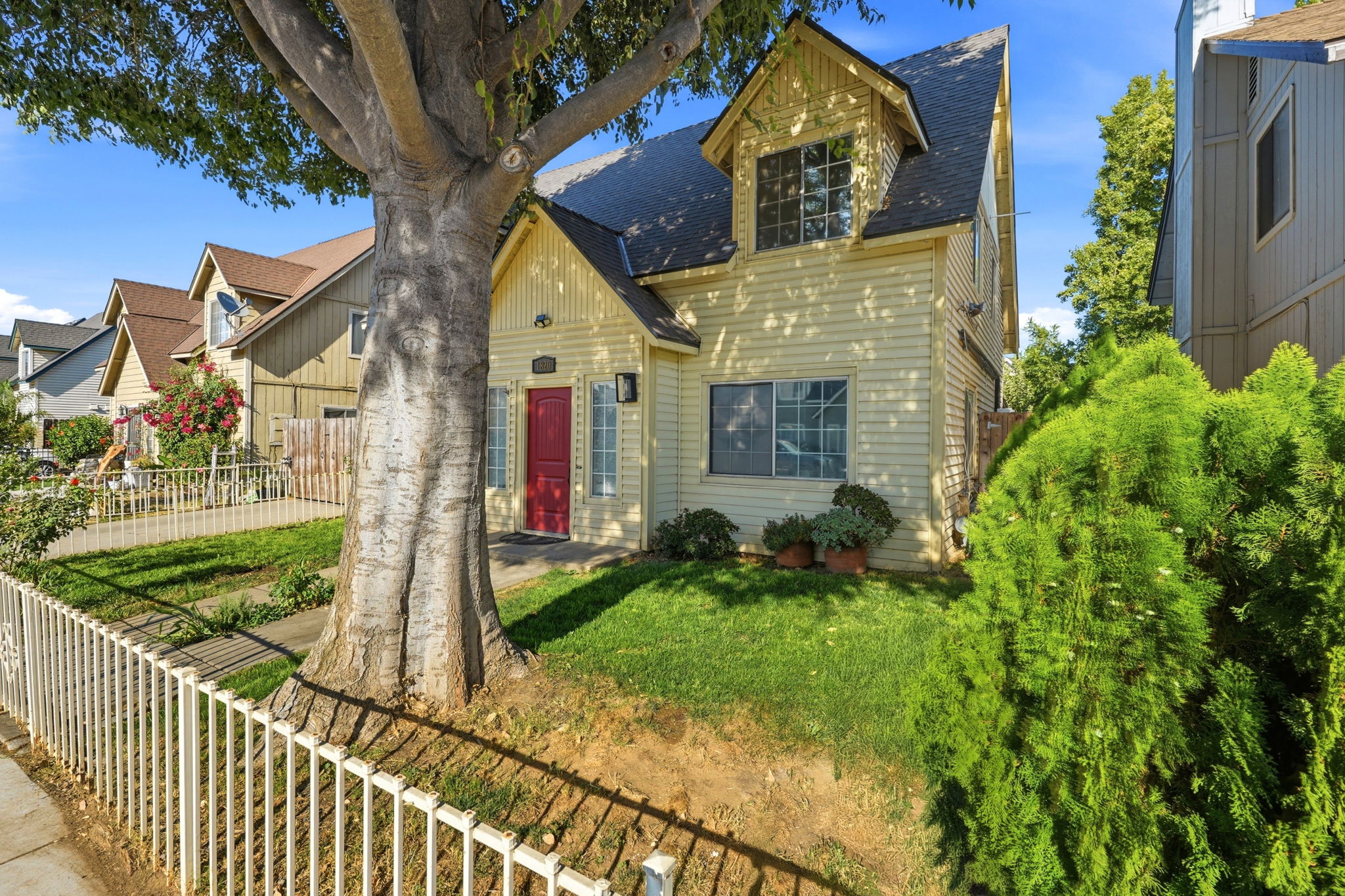 Angled front exterior with fenced lawn and mature shade tree