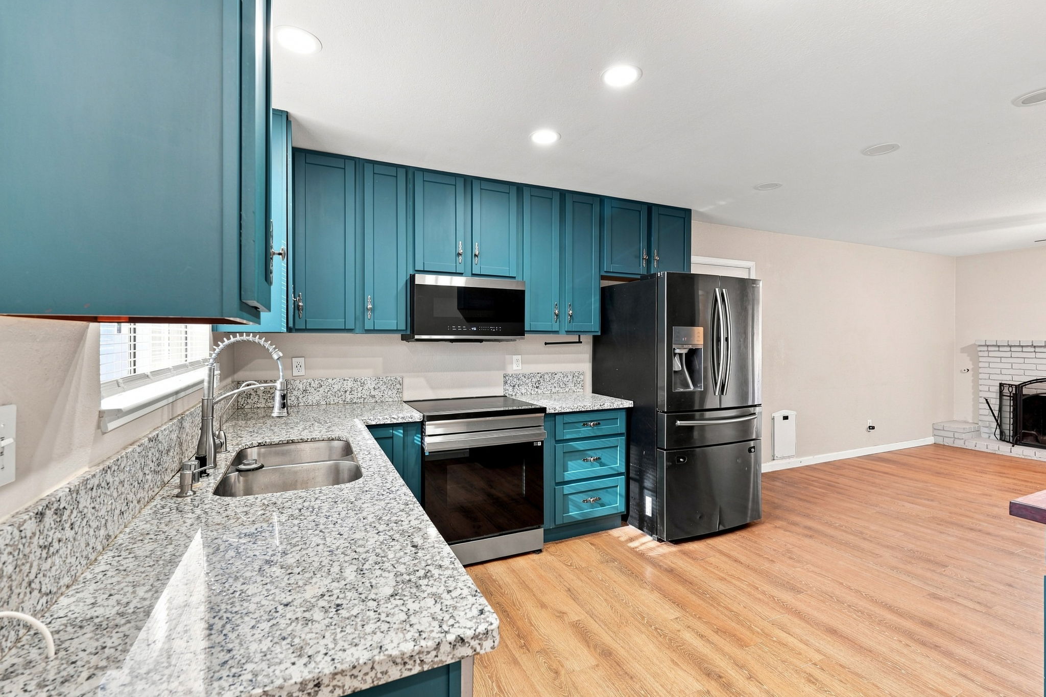 Kitchen with teal cabinetry and granite countertops