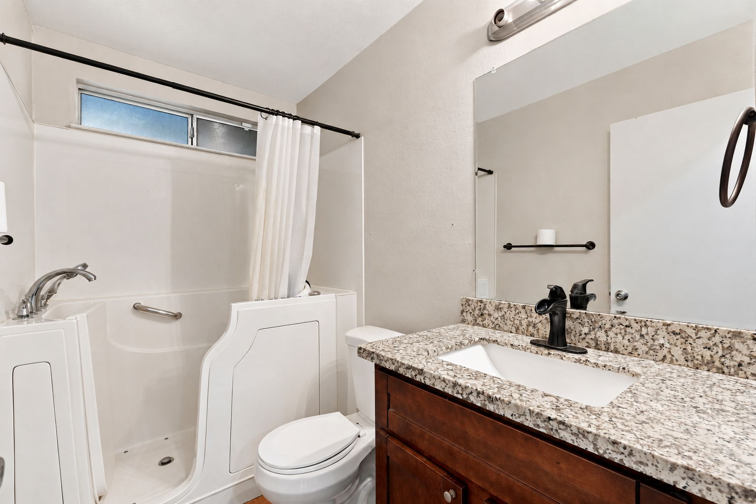 Downstairs full bathroom with walk-in jetted tub and granite-topped vanity