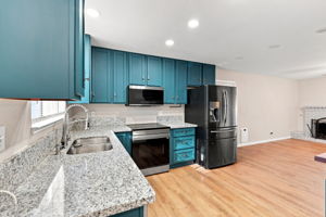 Kitchen with teal cabinetry and granite countertops
