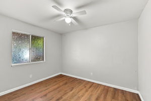 Downstairs Bedroom 1 with wood-look flooring and ceiling fan