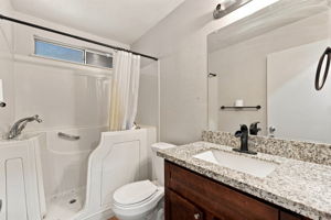 Downstairs Full bathroom 1 with step-in tub and granite-topped vanity