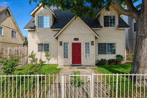 Front exterior with red entry door and mature shade tree