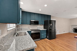 Kitchen with teal cabinetry, granite countertops, and stainless-steel appliances