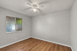 Downstairs bedroom with wood-look flooring and ceiling fan