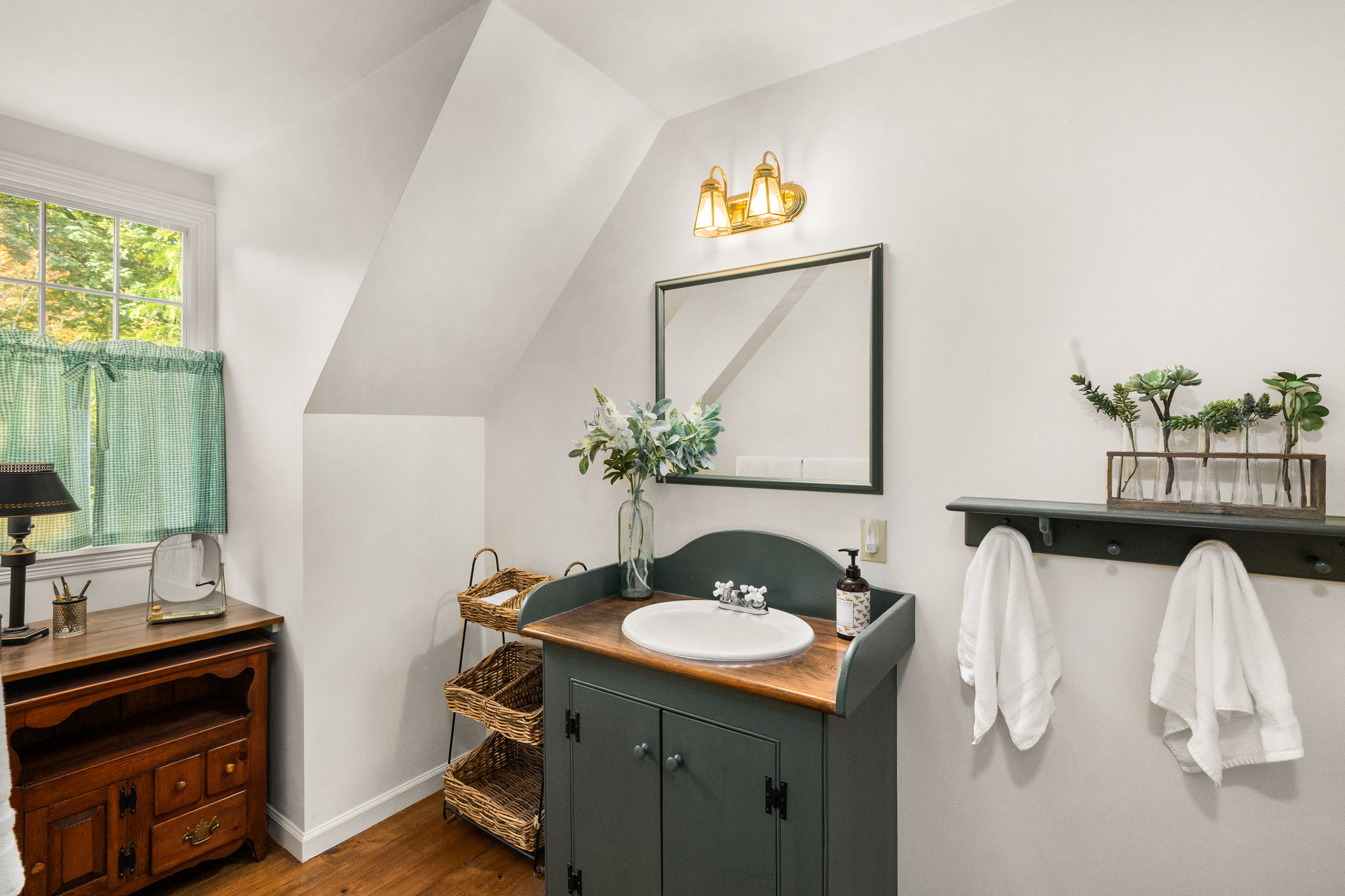The separate wing’s dedicated full bath pairs a wood-topped vanity with soft natural light.