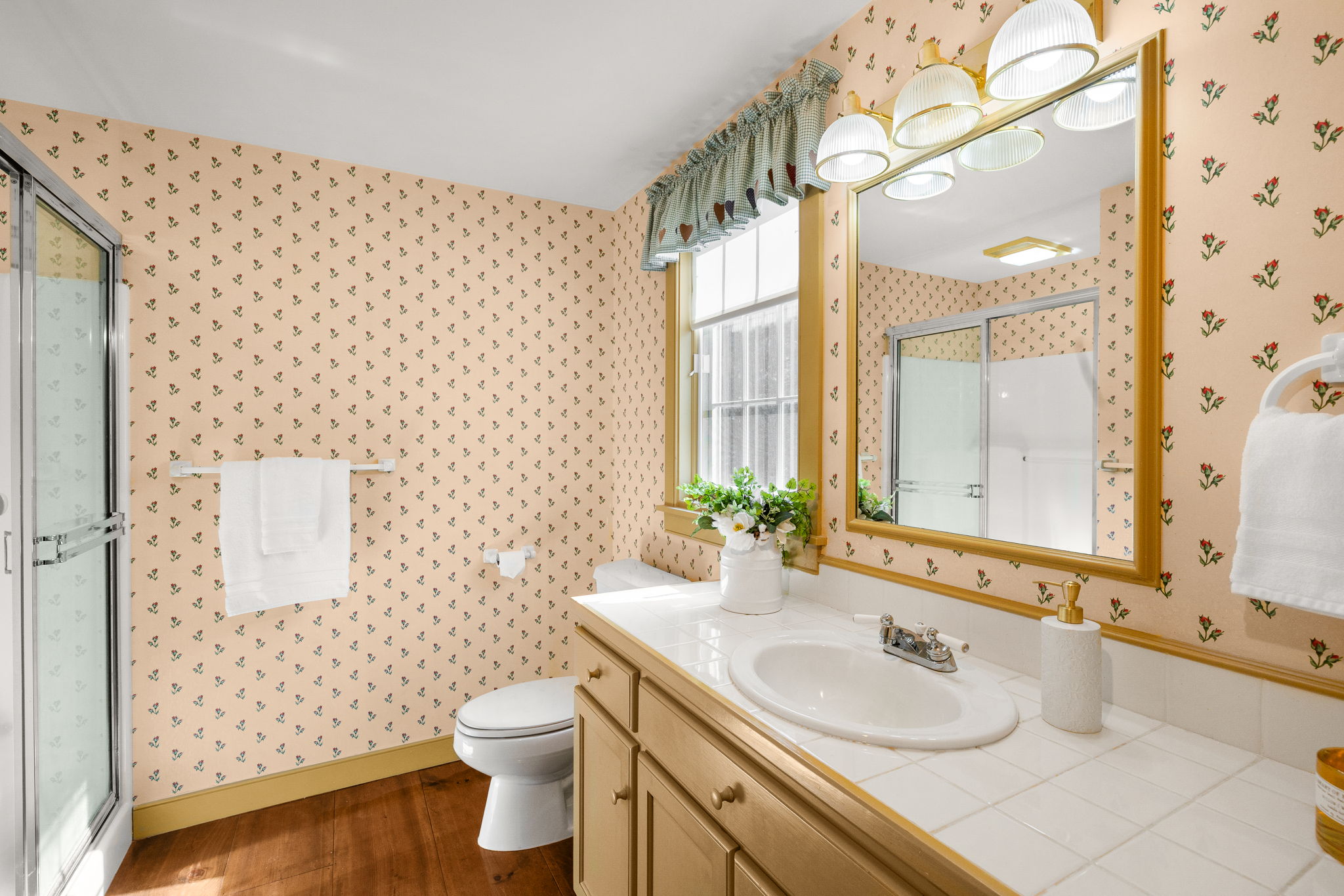 The primary three-quarter bath features a spacious vanity and a glass-enclosed shower.