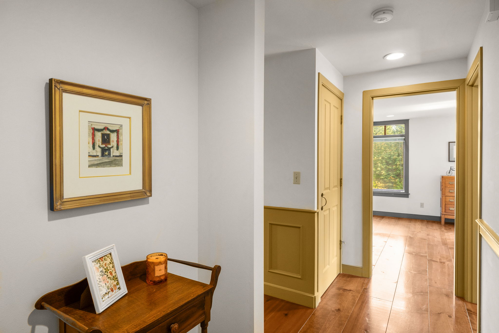 A hallway with warm wood floors and classic trim connects the second-floor bedrooms.