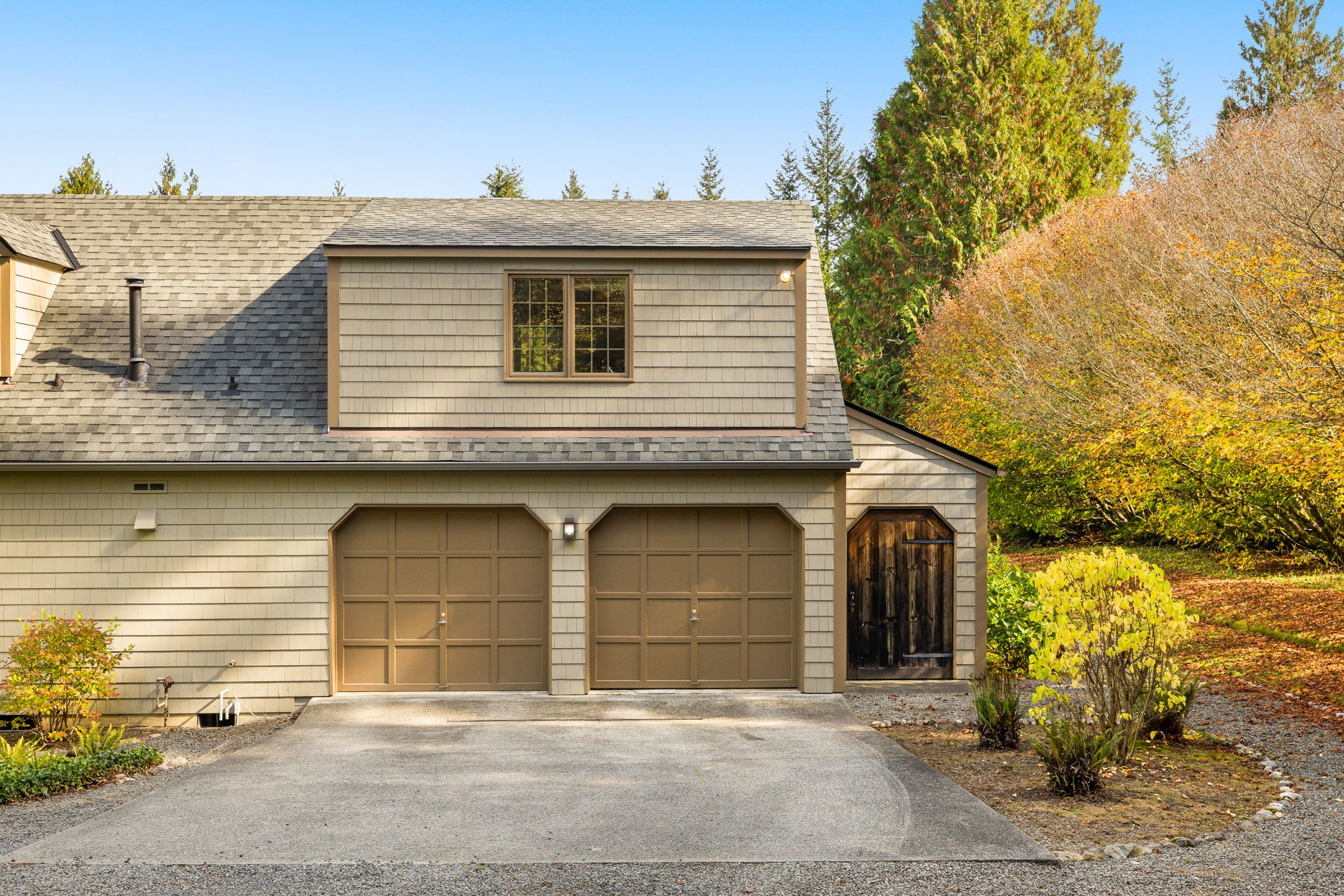 A rustic wood door beside the garage adds charm and opens to additional storage.