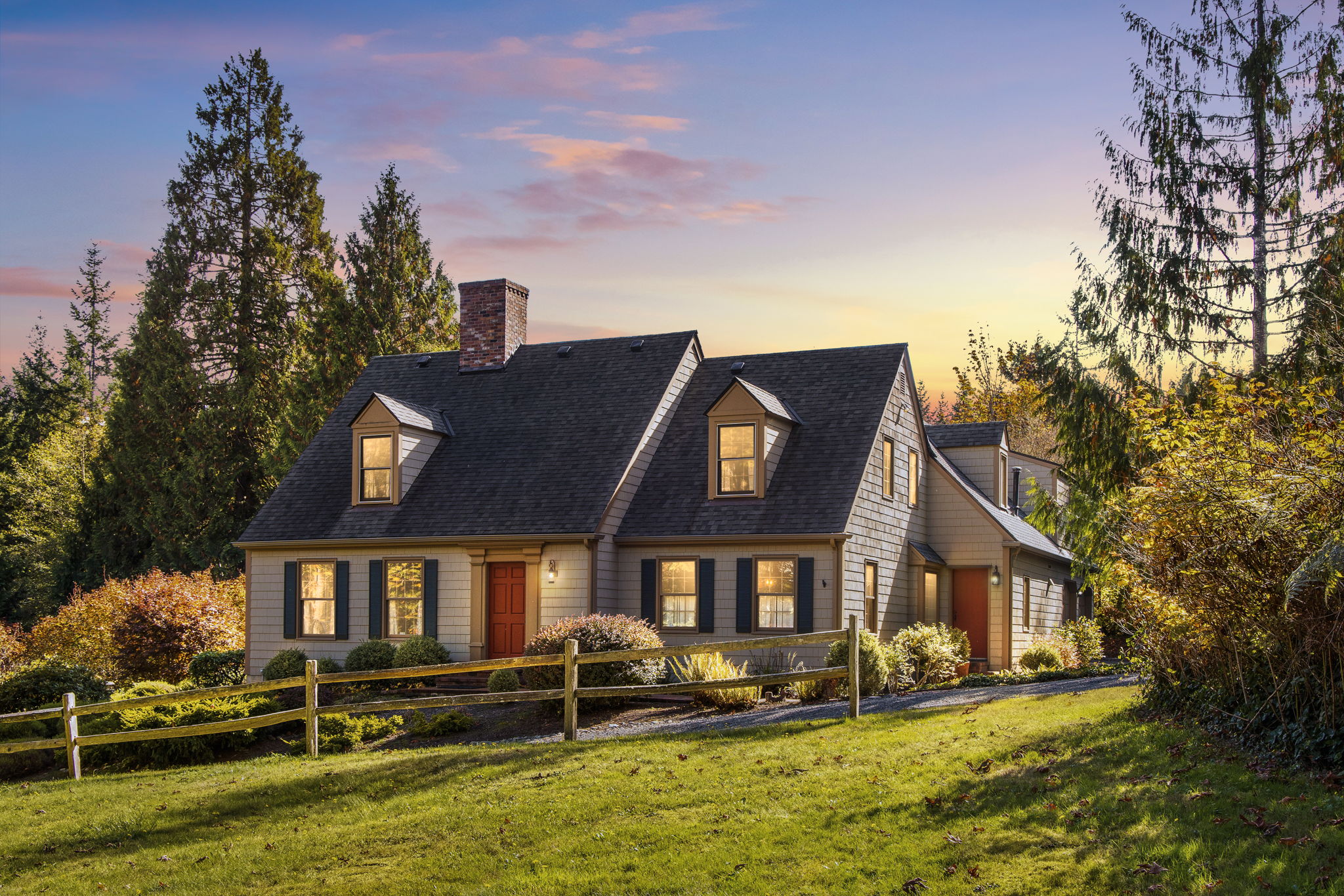 As evening settles in, glowing windows and a softly colored sky bring this charming home to life.
