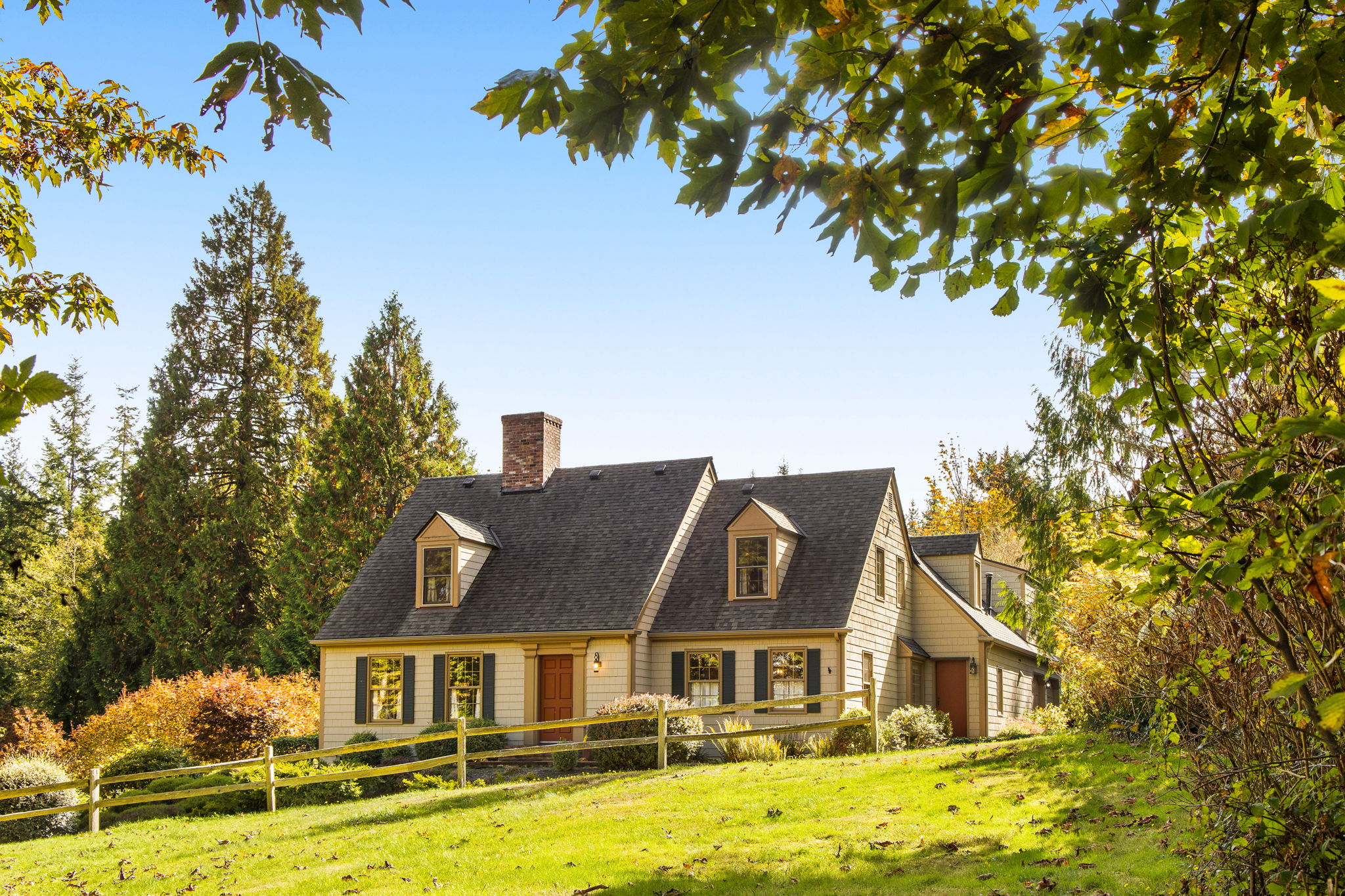 Classic dormers, a brick chimney, and a split-rail fence give this Cape Cod home on five acres timeless country charm.