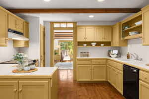 Warm golden cabinetry and open shelving bring charm to the kitchen, with the family room just beyond.