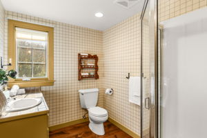 The second-floor hall three-quarter bath features a glass-enclosed shower and ample natural light.