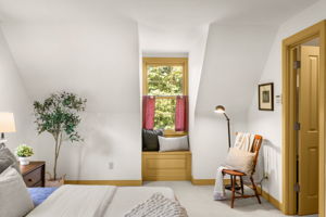 A cushioned dormer window seat overlooks the entry drive, with one of the primary bedroom’s two closets to the right.