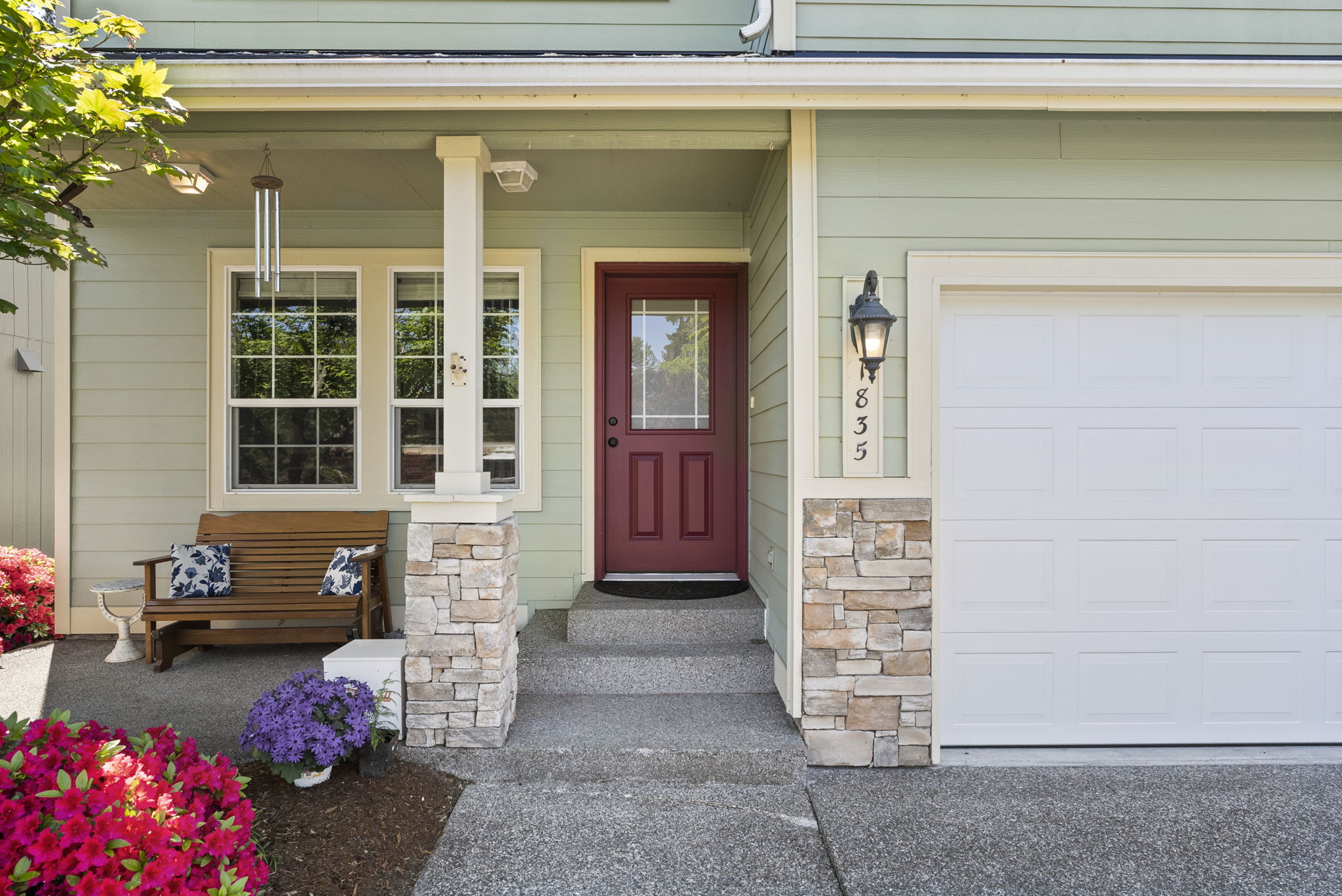 Cozy covered front porch with seating and beautiful landscaped views