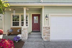 Cozy covered front porch with seating and beautiful landscaped views