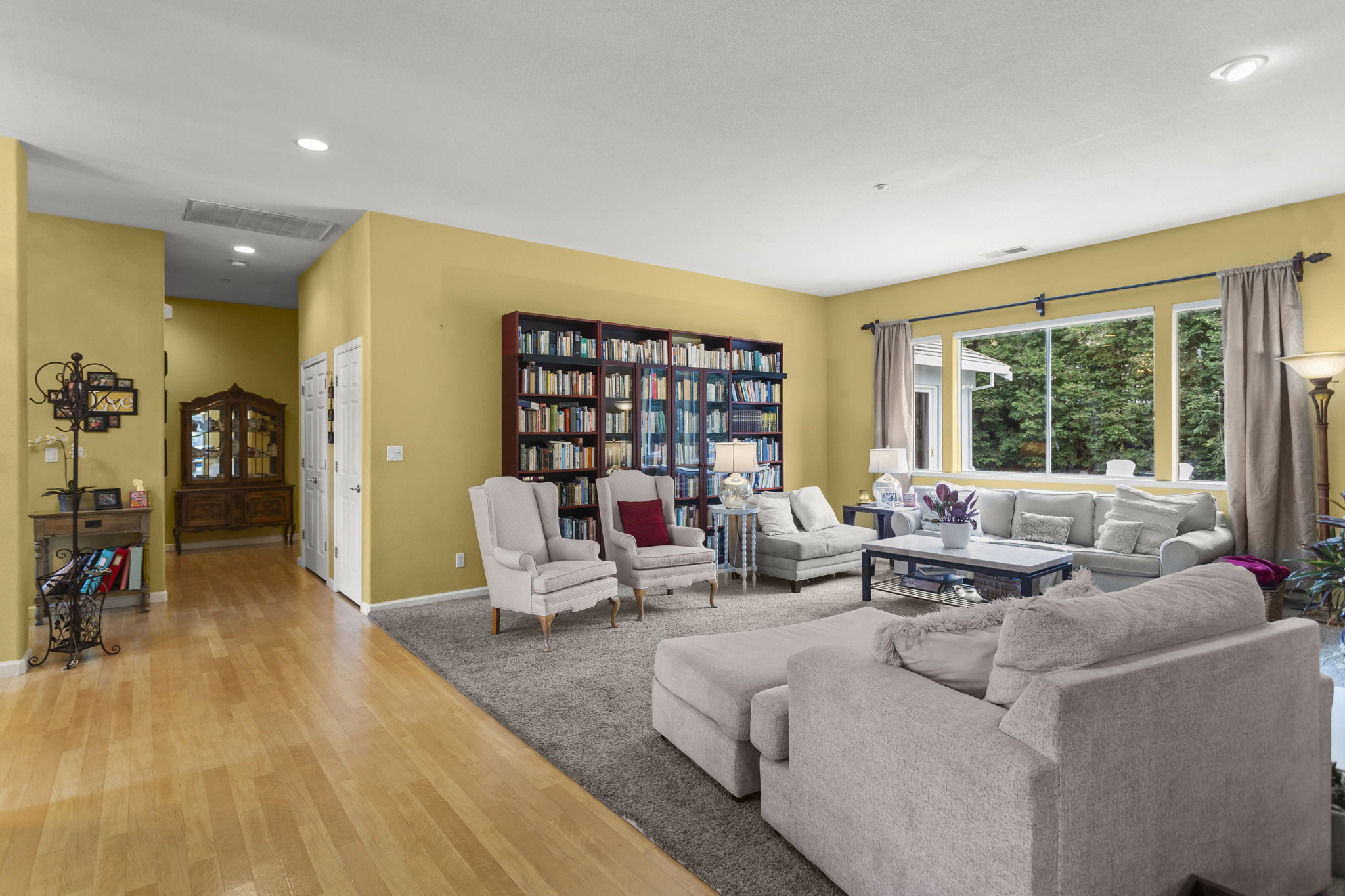 Living room & view to hallway leading towards primary & secondary master bedrooms, laundry, garage, etc.