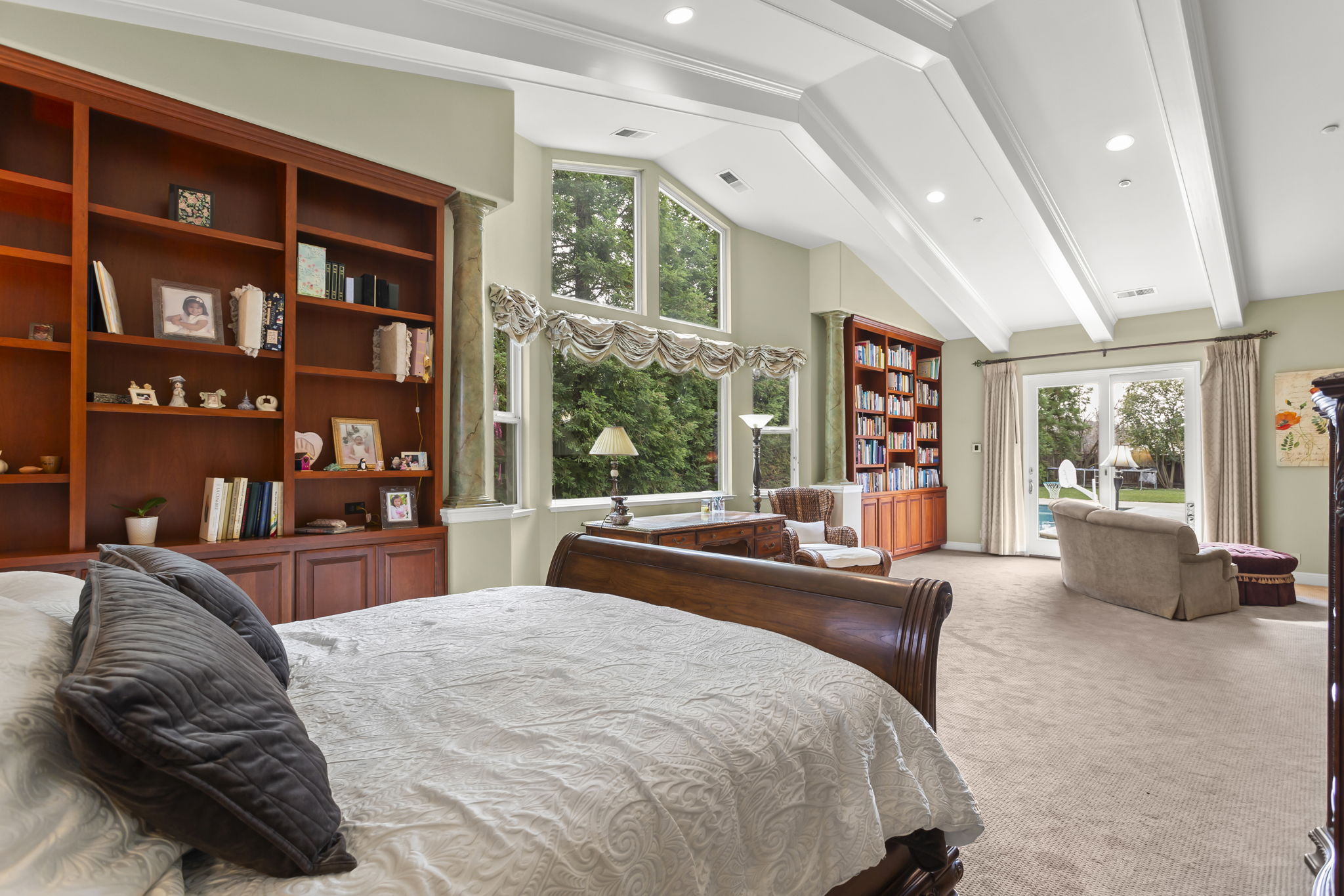 Primary master suite. Windows on left overlook serene left side of backyard. To right, sitting area overlooking pool/spa area through French doors