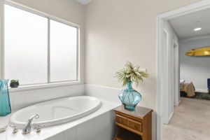 Secondary master bedroom's bath suite with separate shower & tub. Hall past closets, commode area towards bedroom area.