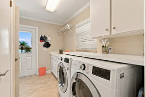 Laundry room with built-in cabinets, countertop & storage closet