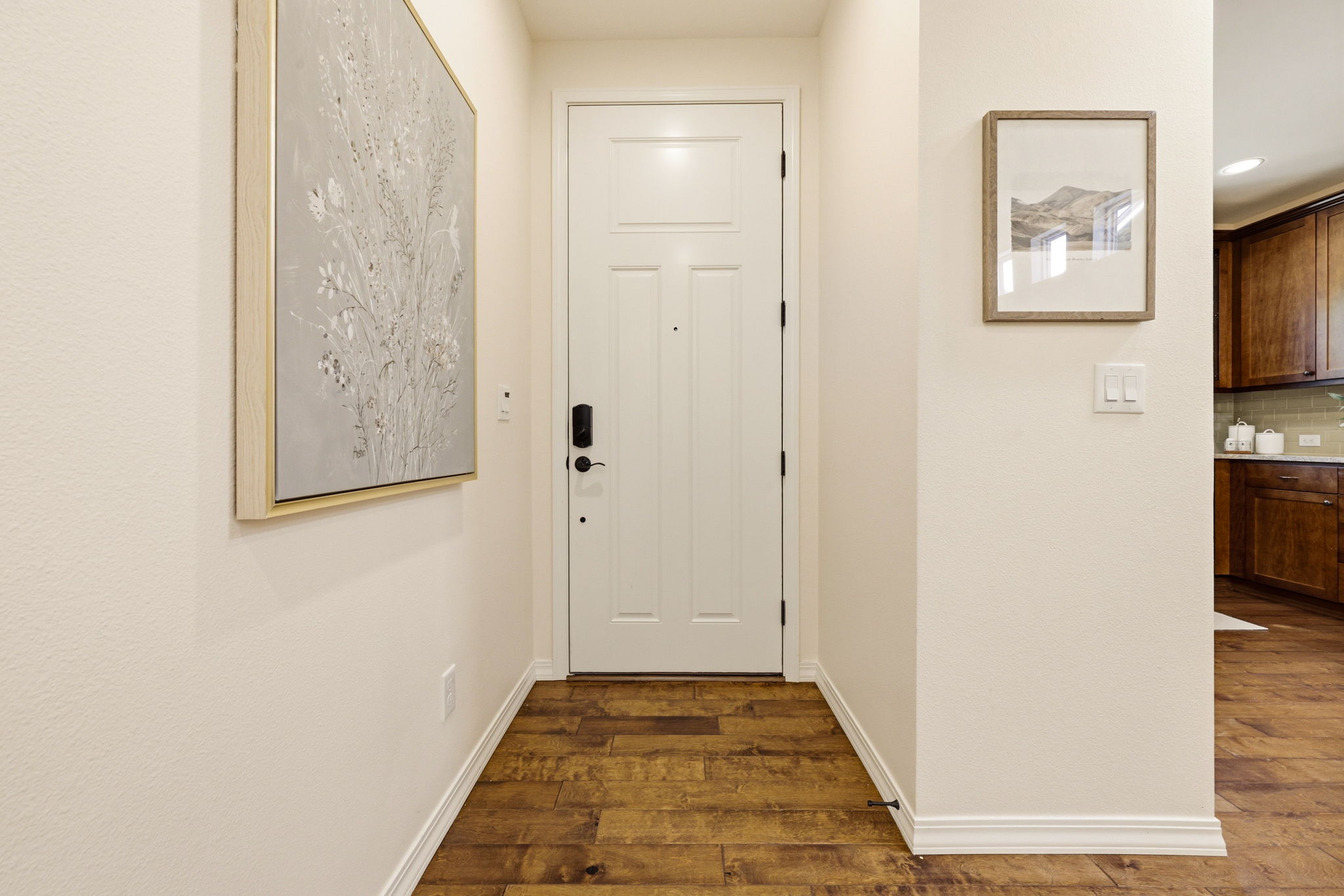 Foyer. Rich hardwood flooring and a designated art wall set a polished tone right from the entrance.