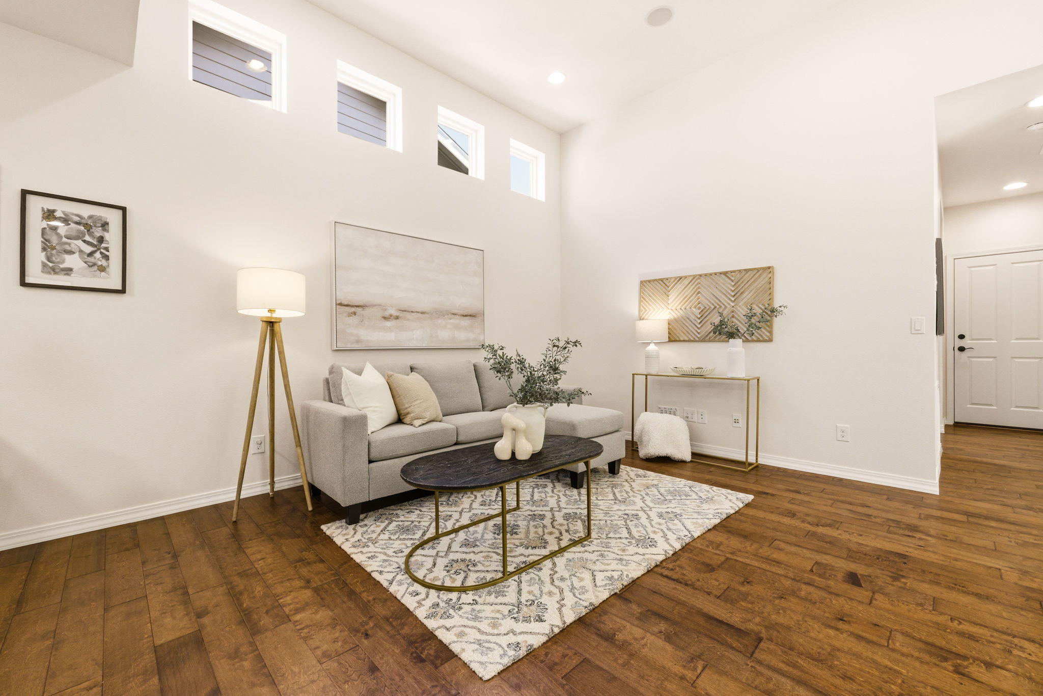 Living Room. Soft neutral tones and a plush area rug create a relaxed gathering space beneath tall clerestory windows.