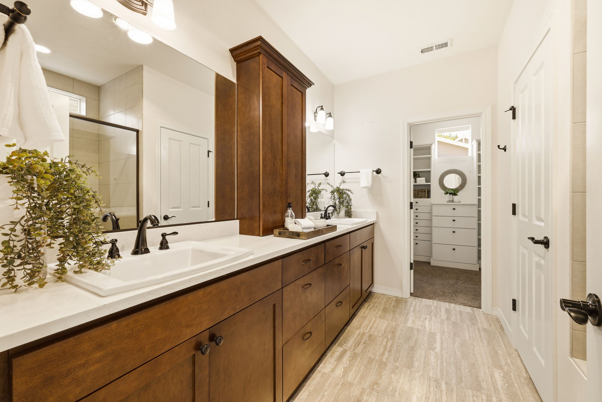 Primary Bathroom. Dual vanities and rich wood cabinetry offer plenty of space to get ready, with direct access to the walk-in closet.