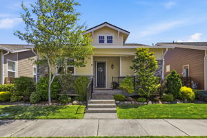 Front Exterior. Craftsman-style curb appeal with stone accents, a covered entry, and lush, professionally landscaped grounds.
