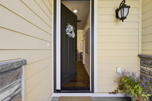 Entry. A rich statement front door opens to a warm welcome, complemented by stone detailing and soft exterior lighting.