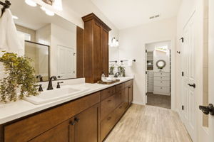Primary Bathroom. Dual vanities and rich wood cabinetry offer plenty of space to get ready, with direct access to the walk-in closet.