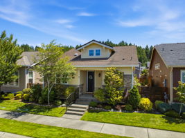 Aerial View. An elevated angle highlights the home's covered entry, landscaping, and wooded backdrop.
