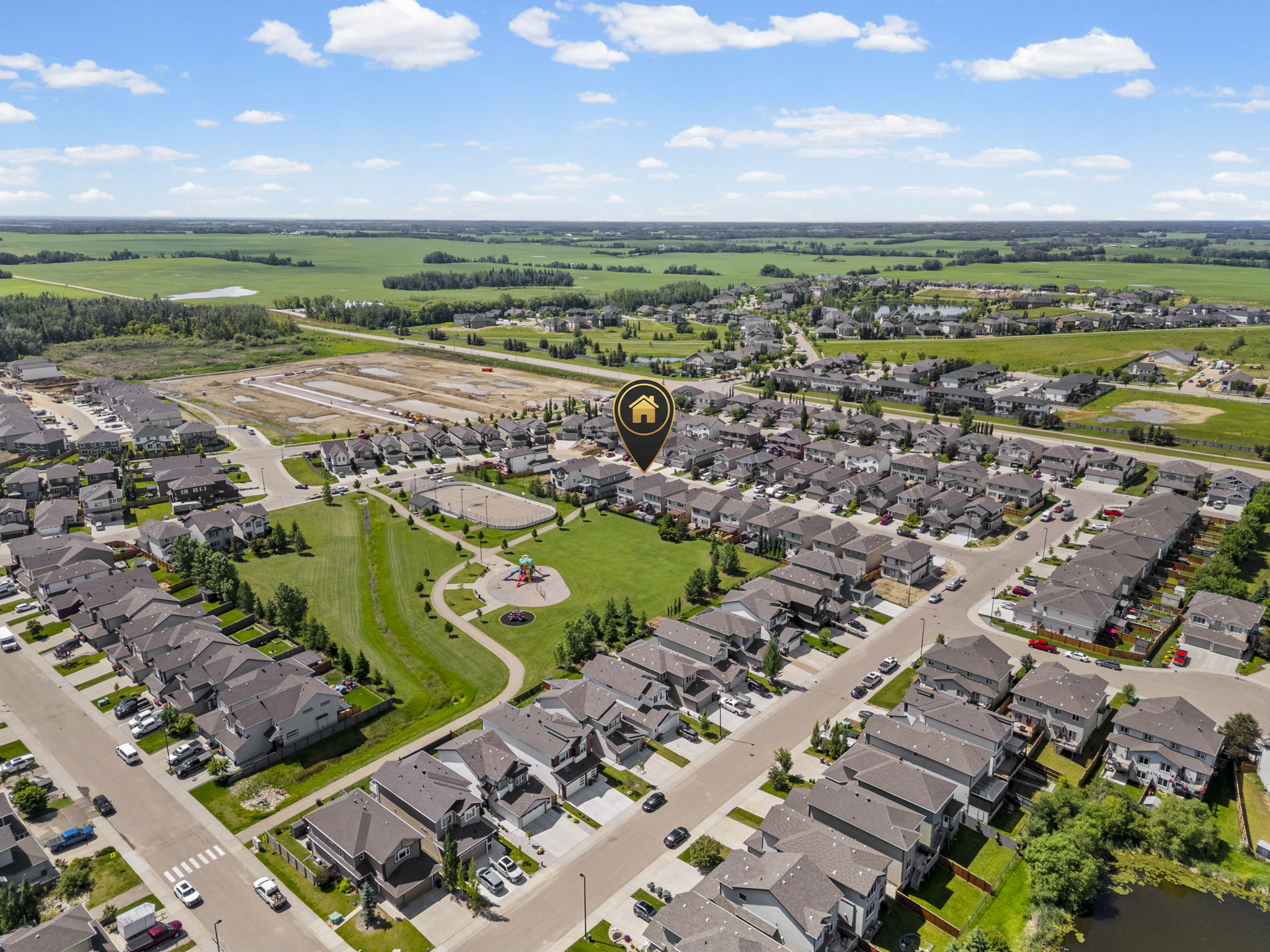 Neighbourhood aerial with a property marker and open fields beyond.