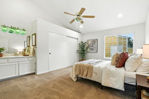 Primary bedroom with attached vanity sink and vaulted. ceilings