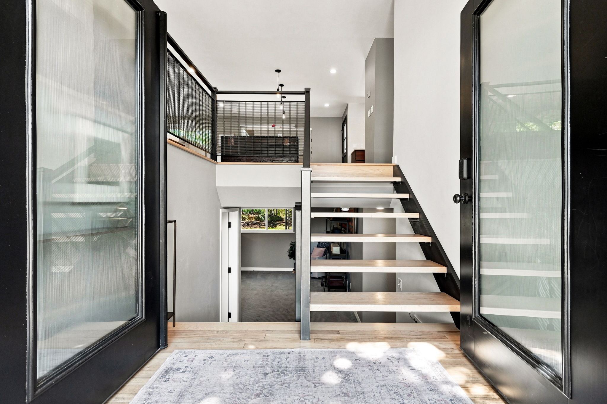 A custom wood-and-steel open staircase greets you at the door.