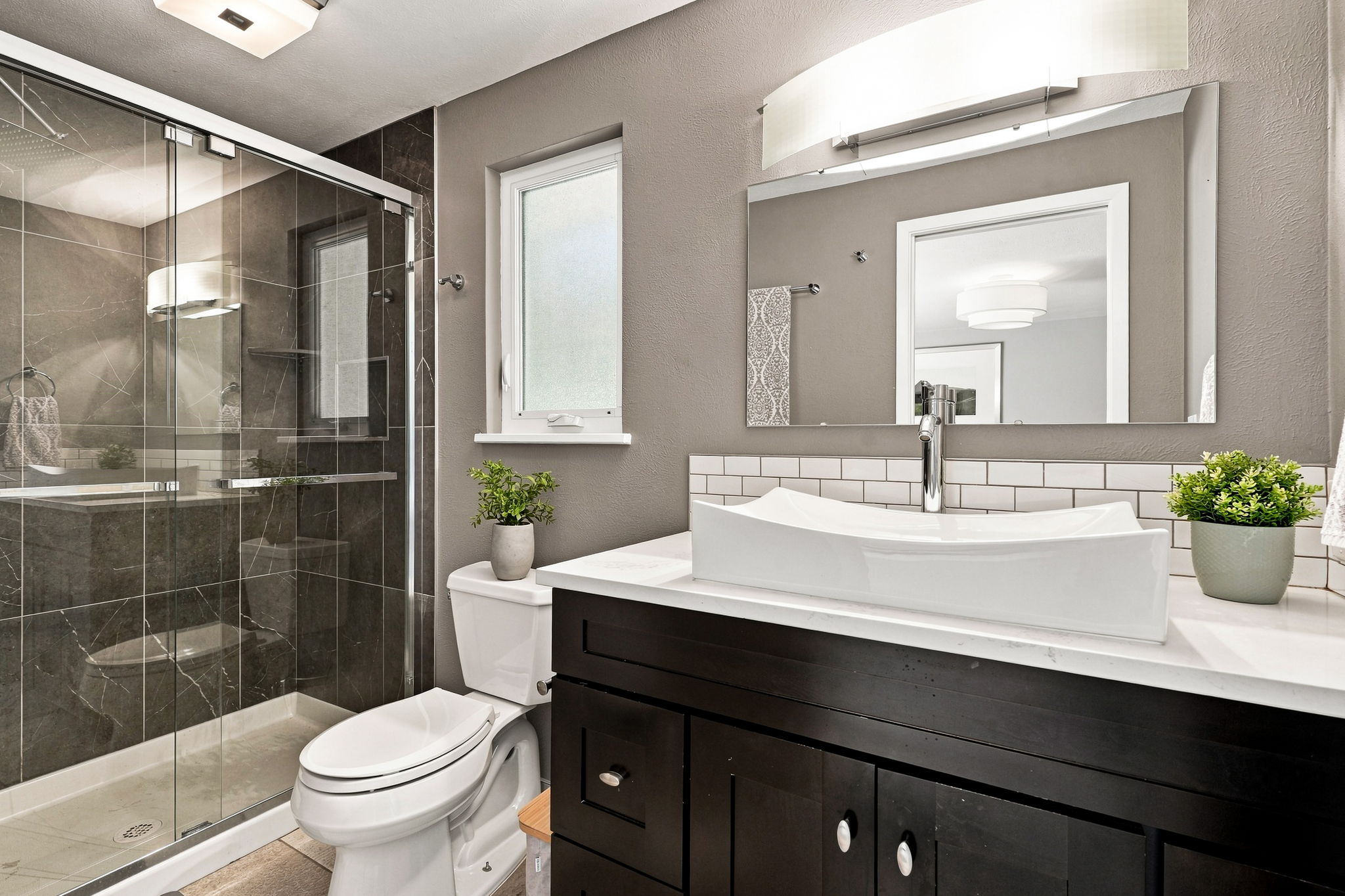 Renovated en suite with a marble-tiled shower and vessel sink.