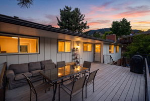 Elevated deck and glowing interiors as the sun drops behind the ridge.